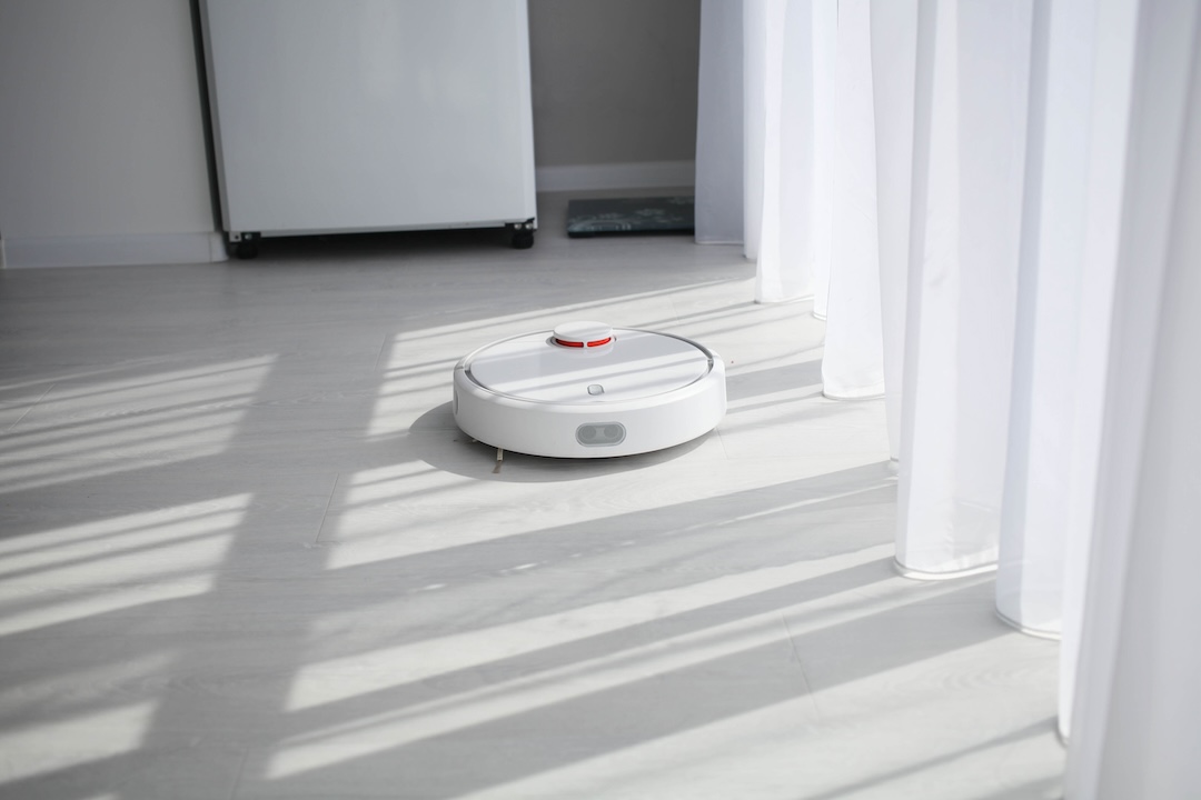 Robot vacuum cleaner cleans on a bright floor. Smart House