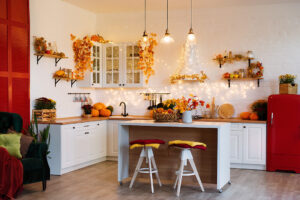 Autumn kitchen interior. Red and yellow leaves and flowers in the vase and pumpkin on white background.